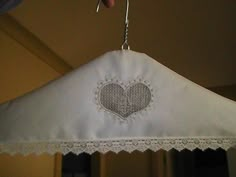 a white cloth hanging from a ceiling with a heart on it and lace trimming around the edges