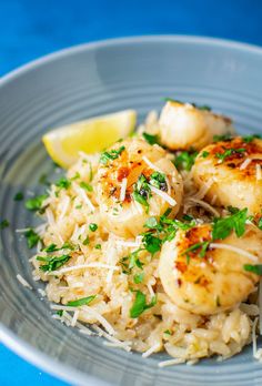 a white plate topped with rice and scallops next to a slice of lemon