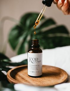 a bottle of kora essentials oil being poured on top of a wooden plate