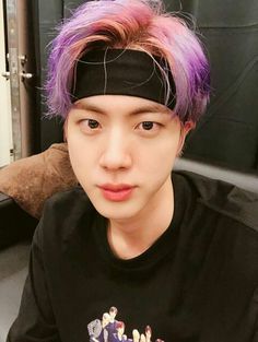 a young man with purple hair wearing a black shirt and headband, looking at the camera