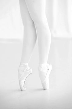 a ballerina's feet in white tights and ballet shoes on a white background