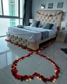 a bed with lights on the floor and a heart made out of red rose petals