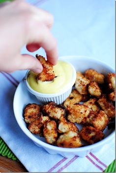 a person dipping something into a bowl with some kind of sauce in it on a plate