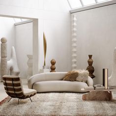 a living room filled with white furniture and large mirrors on the wall next to it