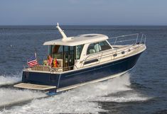 a blue and white boat traveling on the water with an american flag flying above it