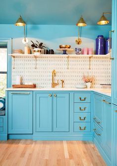 a kitchen with blue cabinets and gold accents on the counters, along with wooden floors