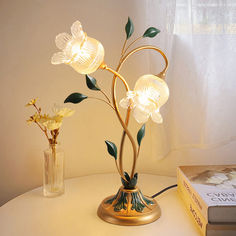 a lamp that is sitting on top of a table next to a book and vase