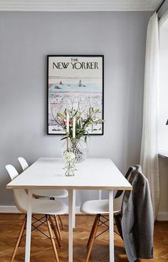 a dining room table with white chairs and a poster hanging on the wall above it