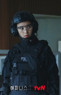 a woman in black uniform and helmet standing next to a wall with the words police written on it