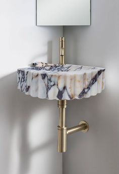 a marble sink with gold faucet and mirror on the wall above it in a bathroom