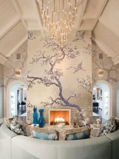 a living room filled with furniture and a fire place under a chandelier hanging from the ceiling