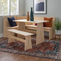 a wooden bench and table in a room with rugs on the floor next to it