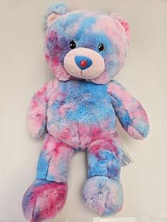 a blue and pink teddy bear sitting on top of a table