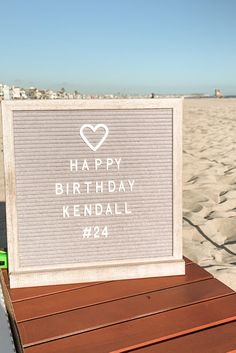 a sign that says happy birthday kendall on the beach with sand in the background