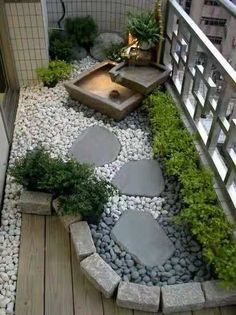 a small garden with rocks and plants on the ground, along with a wooden deck