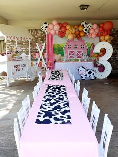 a table set up for a birthday party with balloons and farm animals on the wall