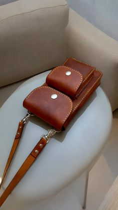 a brown leather case sitting on top of a white table next to a beige couch