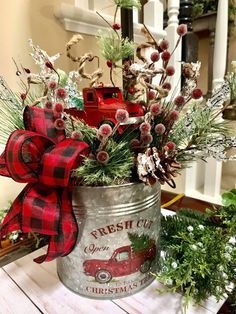 a christmas arrangement in a metal pail on a table