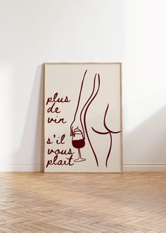 a wine glass is sitting on the floor next to a poster with words written in french