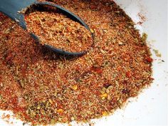 a spoon full of spices on top of a white plate with red pepper flakes