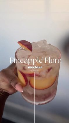 a person holding up a glass with some fruit in it and the words pineapple plum mock