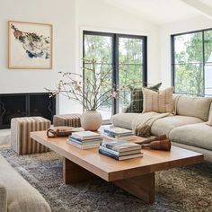 a living room filled with furniture and a fire place in front of two large windows