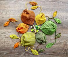 four different colored leaves on a wooden surface with dices and beads in the middle