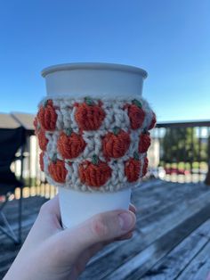 a hand holding up a coffee cup covered in crochet