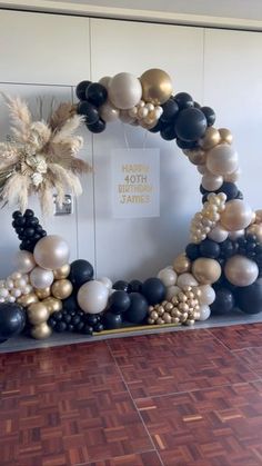 a balloon arch with black, white and gold balloons in the shape of a palm tree