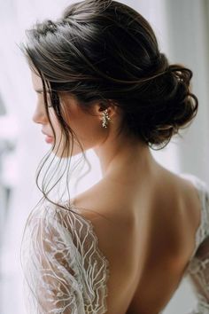 a woman in a wedding dress looking out the window with her back to the camera