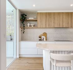 a kitchen with wooden cabinets and white counter tops, along with two stools in front of the bar