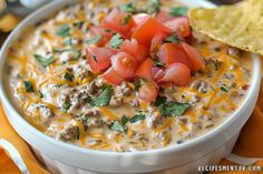 a white bowl filled with cheese and salsa next to a tortilla chip on the side