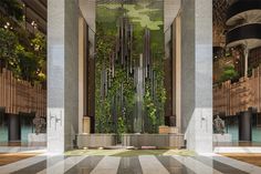 the lobby is decorated with greenery and decorative columns, along with marble flooring