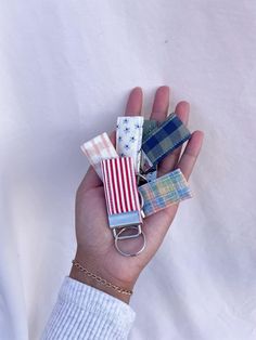 a person holding several small pieces of fabric in their hand, including an american flag keychain