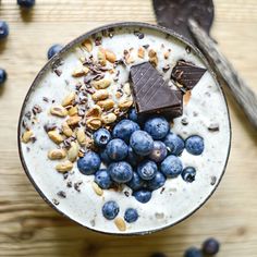 a bowl filled with cereal and blueberries on top of a wooden table next to spoons