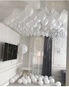 white balloons are hanging from the ceiling in this room