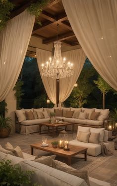 an outdoor living area with couches, tables and chandelier hanging from the ceiling