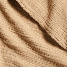 close up view of the texture of a quilted bed sheet with pleated edges