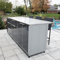 an outdoor kitchen is shown with chairs around it