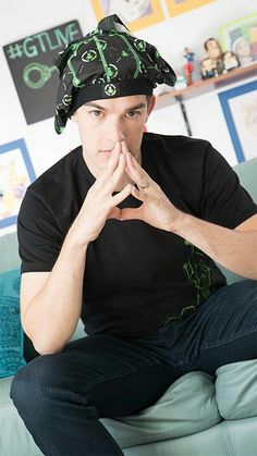 a man sitting on top of a green couch wearing a bandanna hat and black shirt