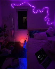 a bed room with a laptop computer on top of it next to a purple light