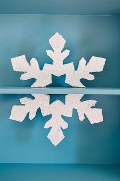 a snowflake is shown on the shelf in front of a blue wall with white shelves