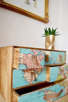 two drawers with maps painted on them and a plant in the corner next to it