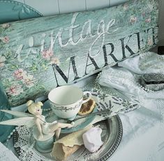 an antique market sign sitting on top of a table next to a cup and saucer