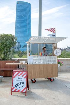 a man standing behind a food cart on wheels