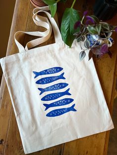 a tote bag sitting on top of a wooden table next to a potted plant