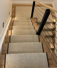 the stairs are lined with beige carpet and black handrails