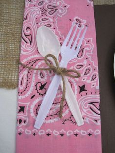 two forks and spoons tied together on a pink bandanna table cloth with brown burlap