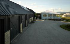 the driveway is lined with black garages and white buildings on either side of it