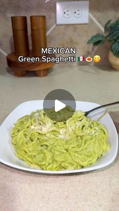 a white plate topped with green pasta and sauce